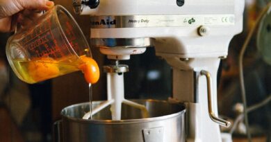 person pouring egg yolks on white stand mixer