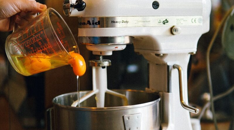 person pouring egg yolks on white stand mixer